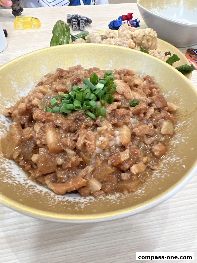 A close-up of a bowl of braised pork rice topped with chopped green onions.