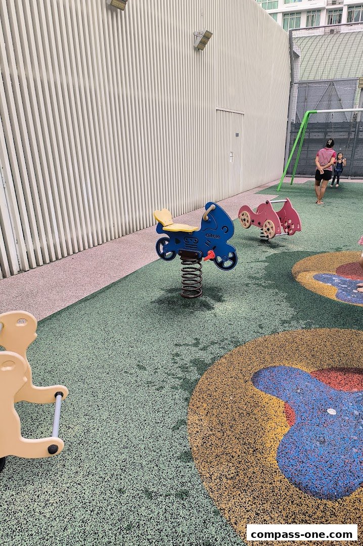 A colorful playground with spring riders and a swing set, featuring a textured rubberized surface.