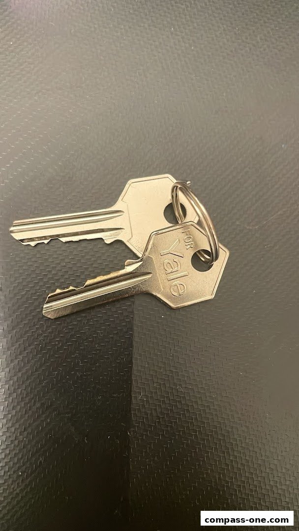 Two silver keys on a dark textured surface, one labeled 'FOR Yale'.