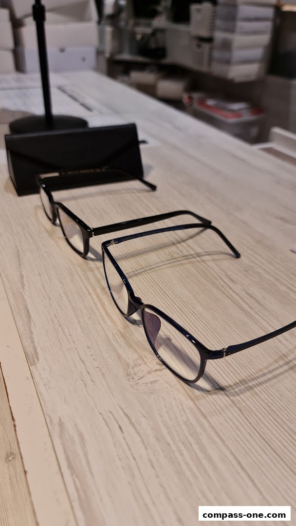 Two pairs of stylish eyeglasses displayed on a wooden surface with a black glasses case.