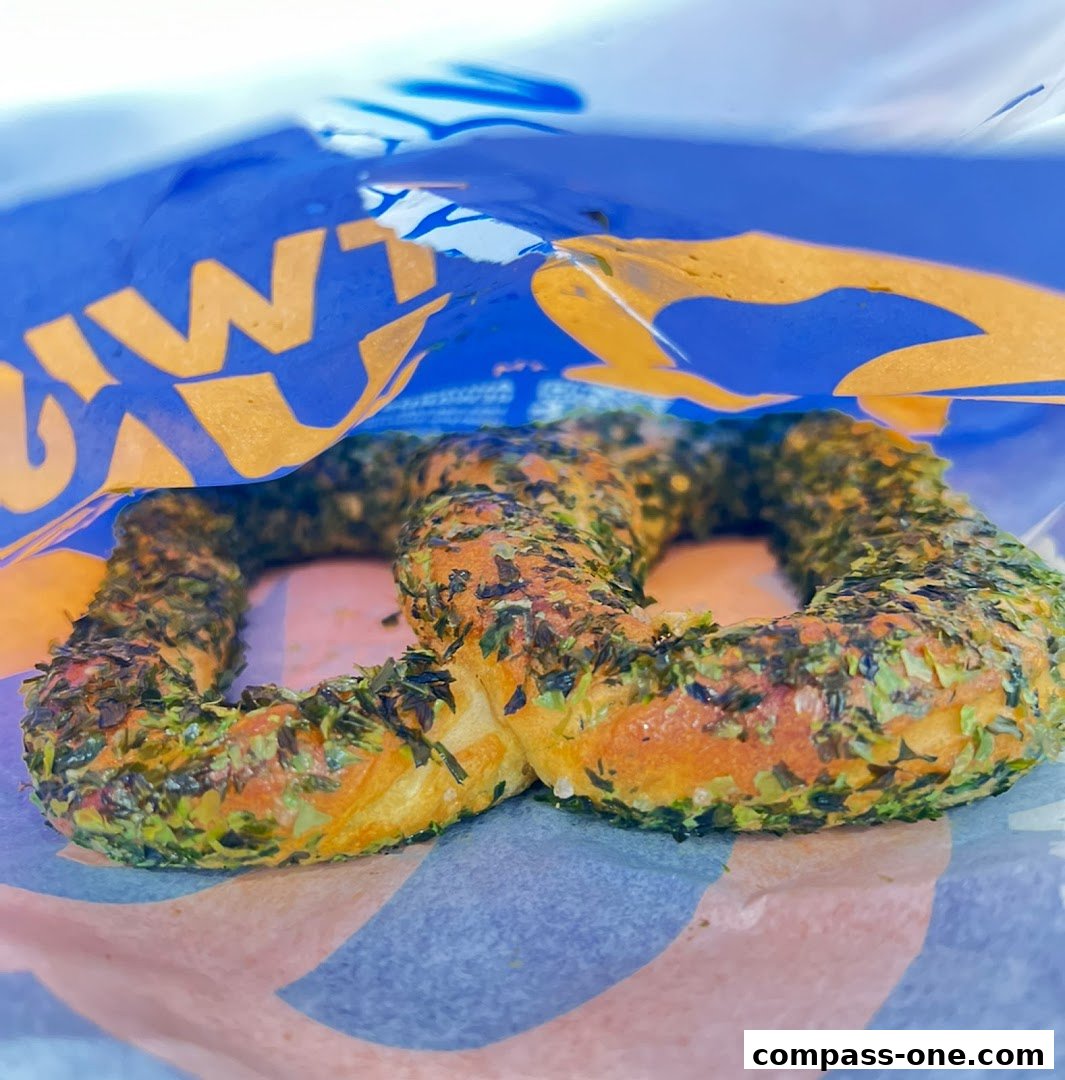 A close-up of a pretzel with green seasoning in a branded bag.