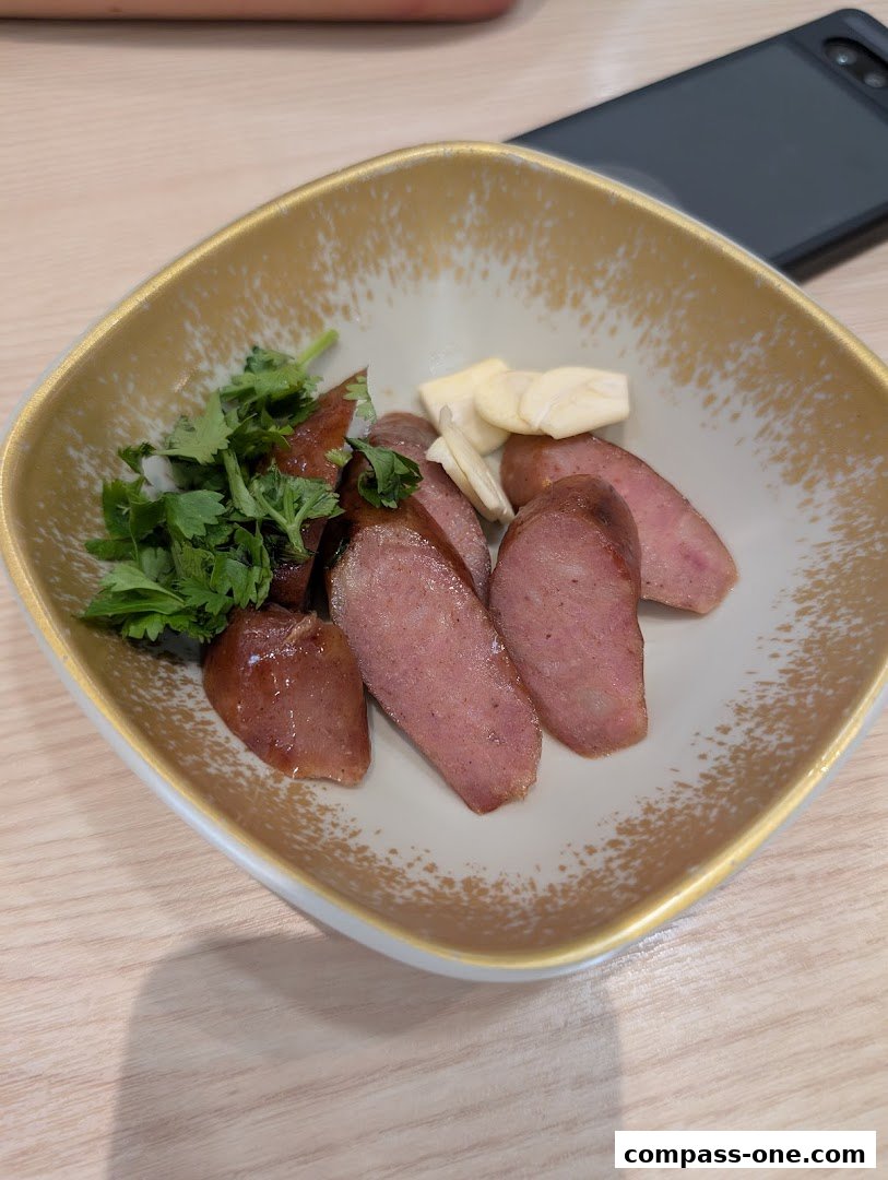 A bowl of sliced sausages with cilantro and garlic on a wooden table.