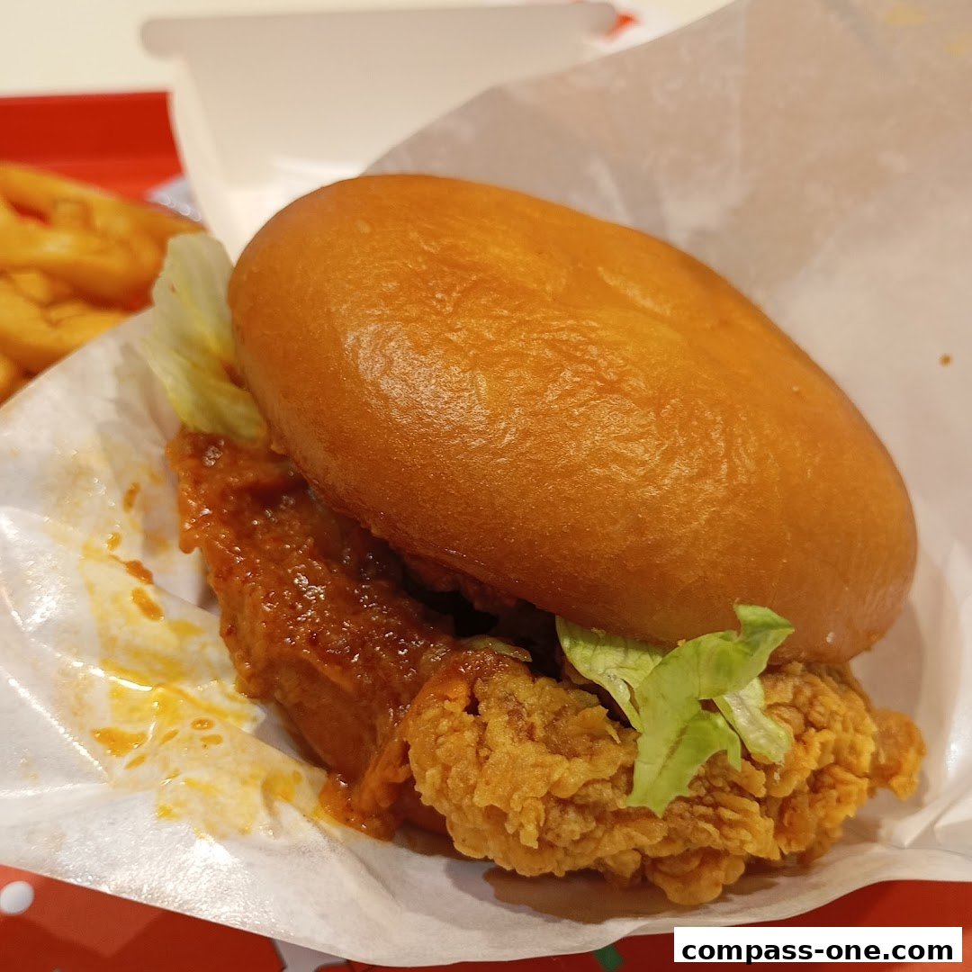A close-up of a delicious KFC chicken burger with crispy chicken and sauce.