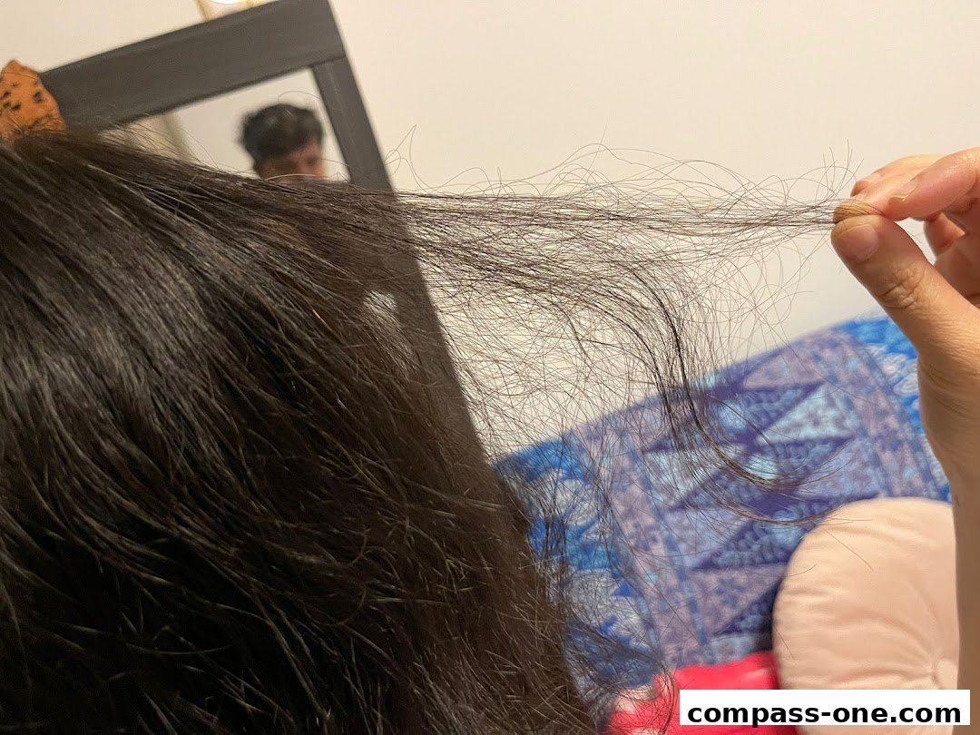 A person holds a section of their hair, showing split ends, with a reflection in a mirror.