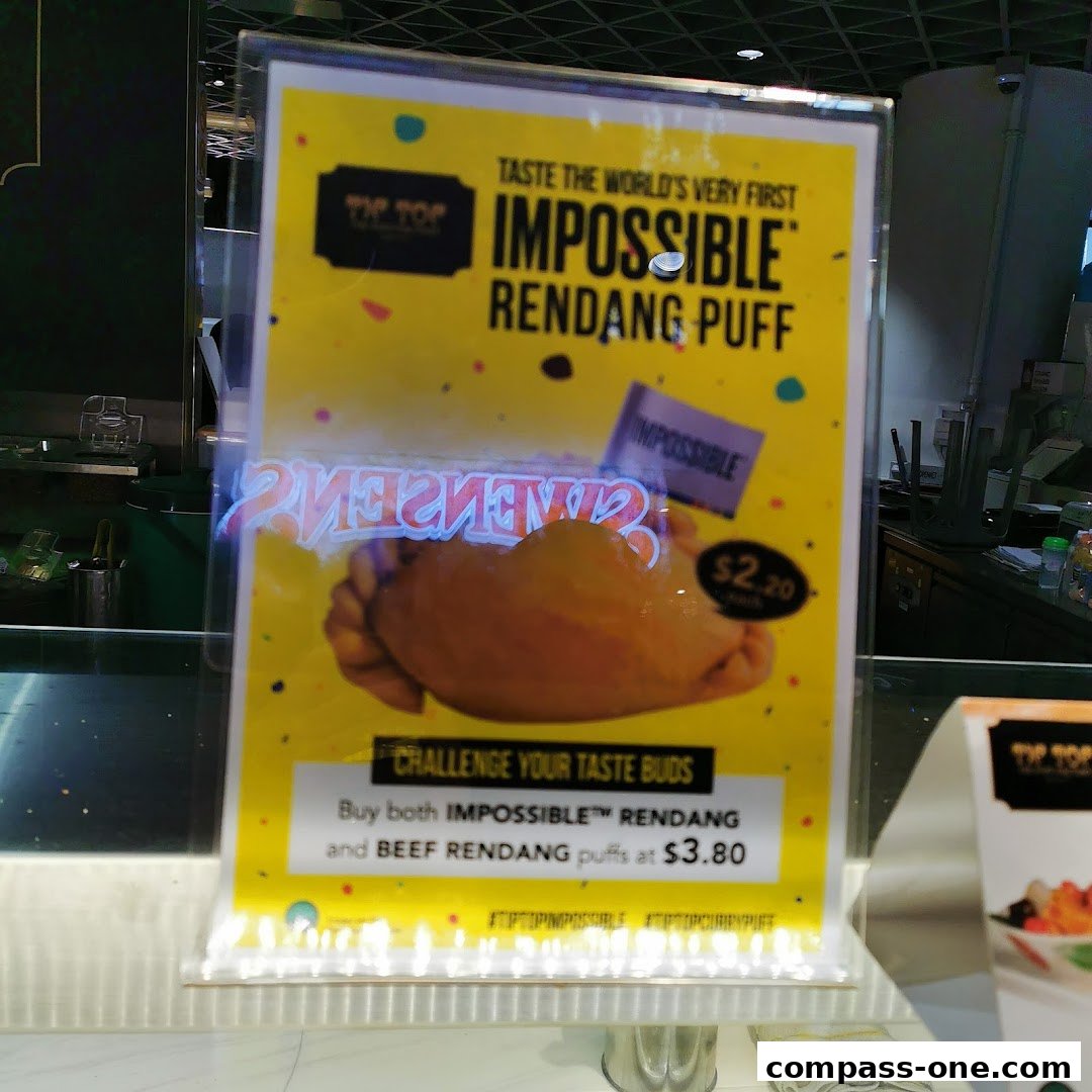 A sign advertising Tip Top Curry Puff's Impossible Rendang Puff and a combo deal.