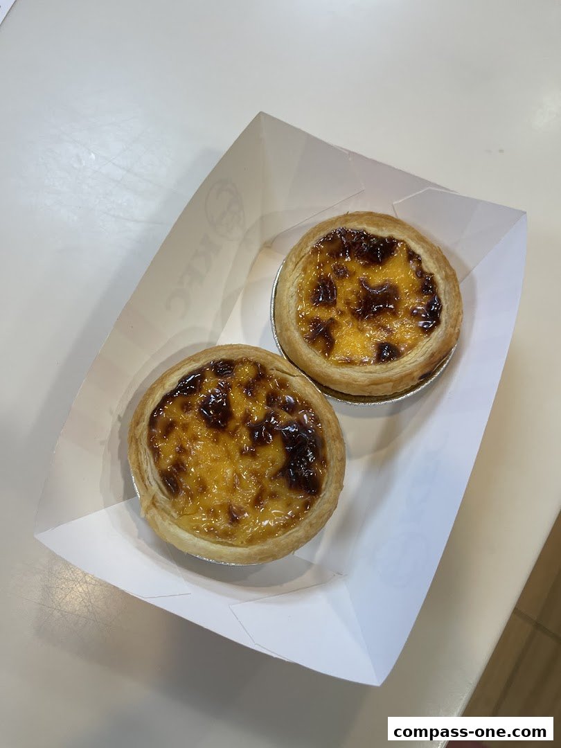 Two delicious-looking egg tarts served in a KFC branded paper tray.