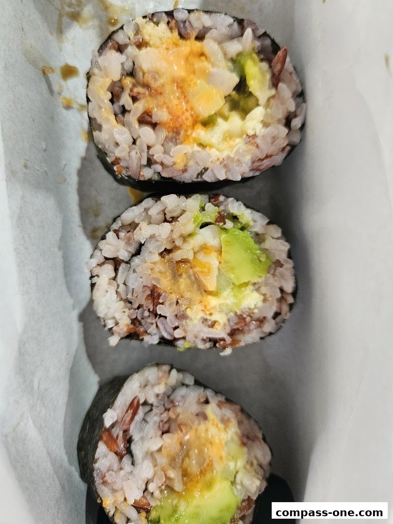 Three pieces of sushi rolls with brown rice, avocado, and a creamy filling.
