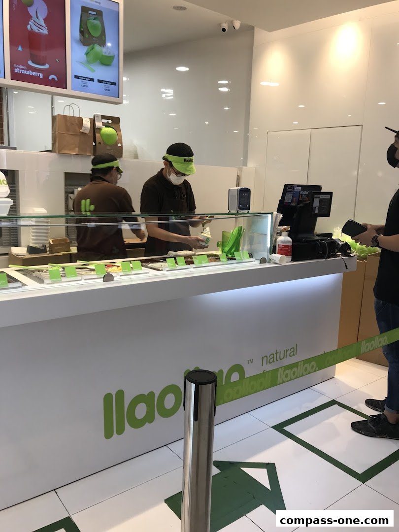 Staff preparing frozen yogurt at the llaollao counter with customers waiting.