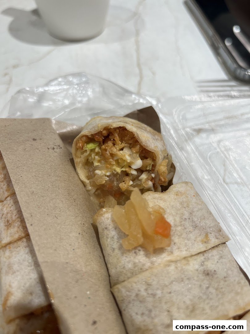 Close-up of a popiah roll, showing its filling and a side of pickled vegetables.