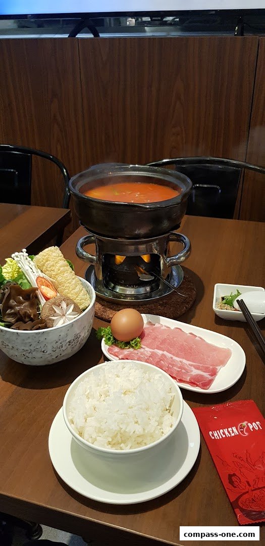 A steaming hotpot meal with fresh ingredients, rice, and meat is ready to be enjoyed.