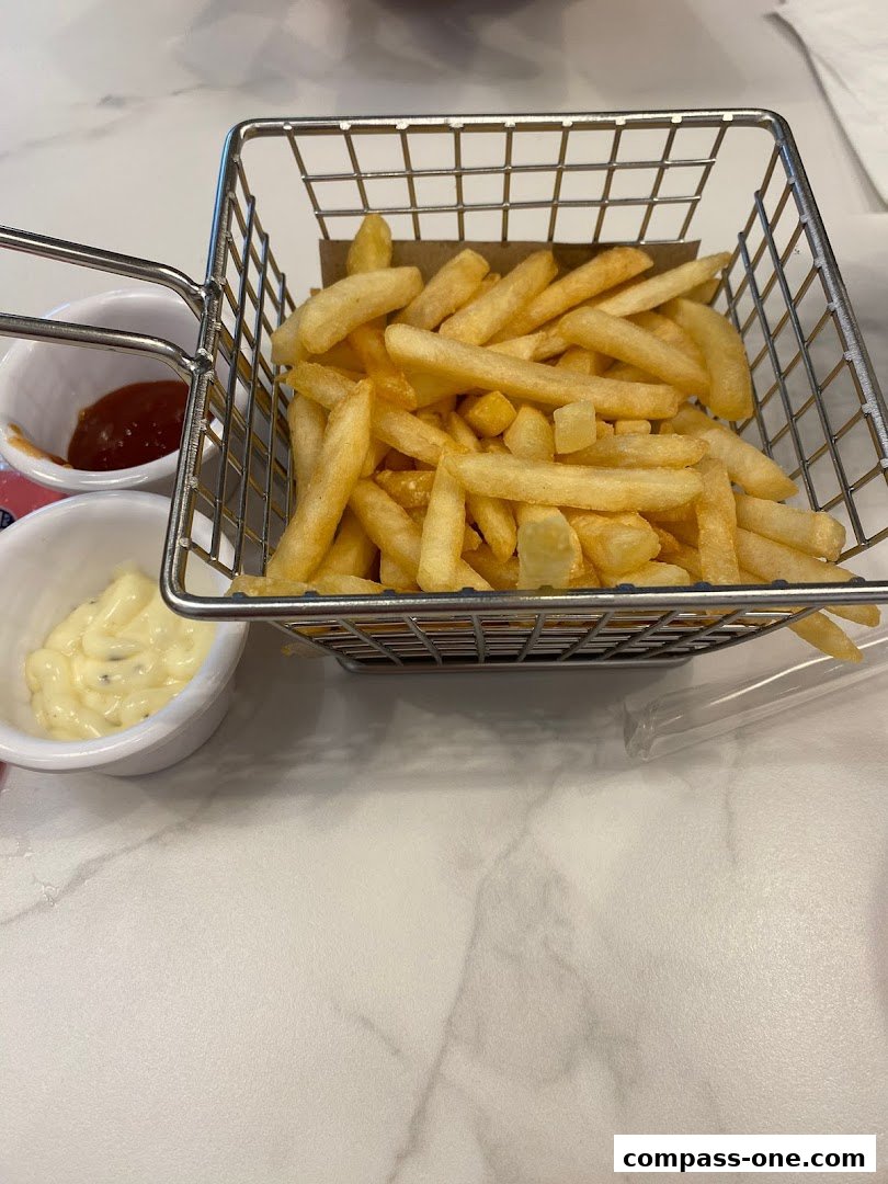 A basket of golden french fries served with ketchup and mayonnaise.