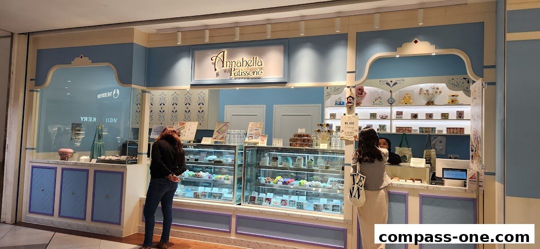 A pastel blue patisserie shop with macarons and cakes displayed in glass cases.