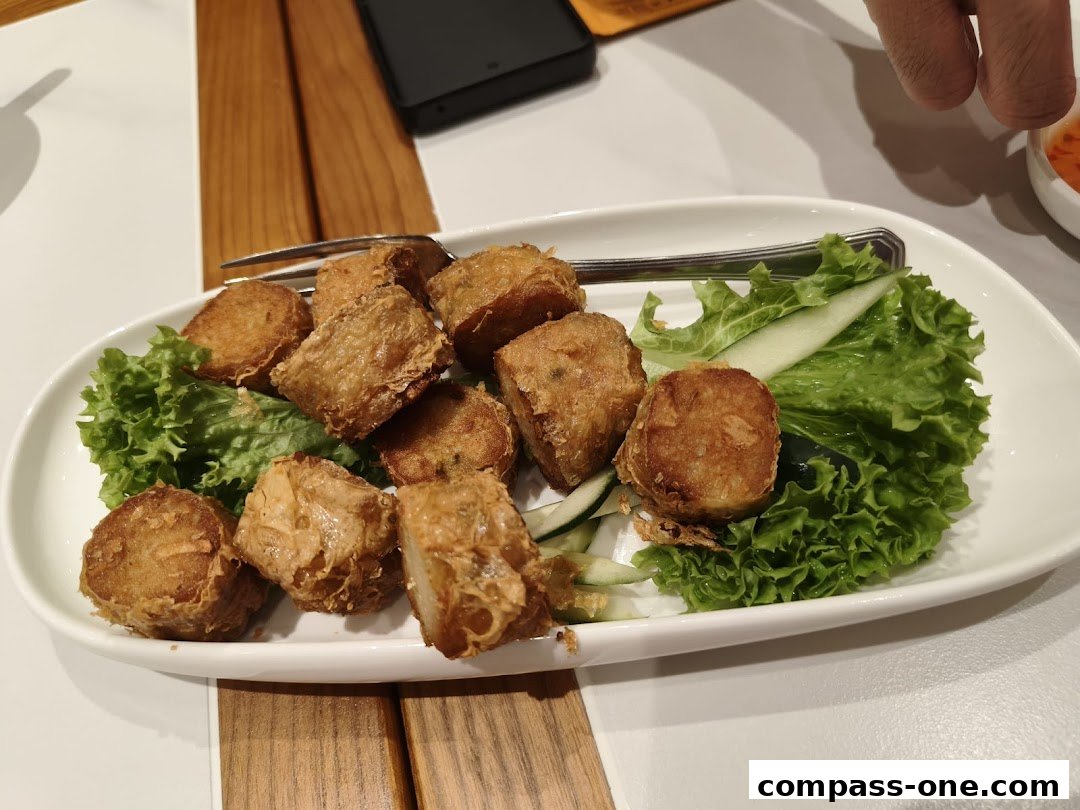 A plate of golden-brown fried spring rolls served with fresh lettuce and cucumber.