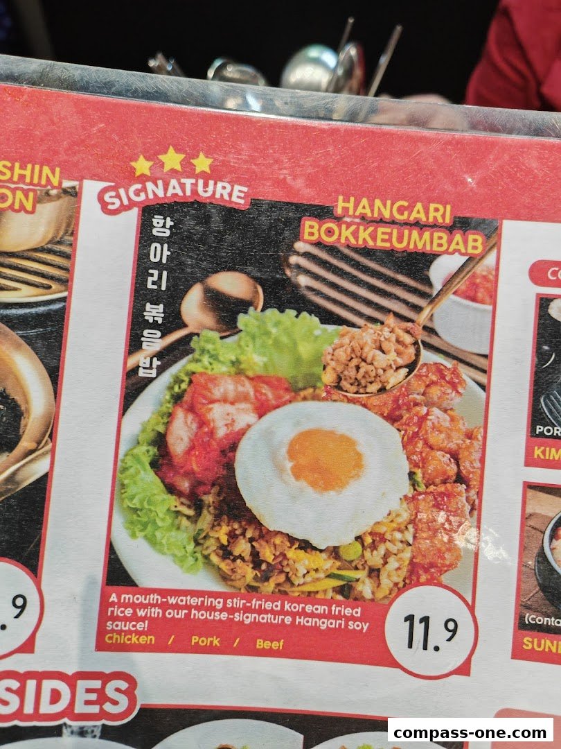 A close-up of a menu item featuring Korean fried rice with meat and a fried egg.