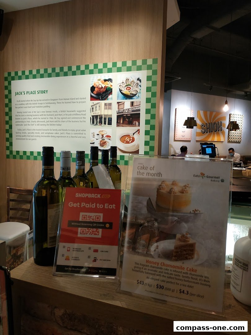 A display inside Jack's Place featuring a cake of the month and a Shopback promotion.