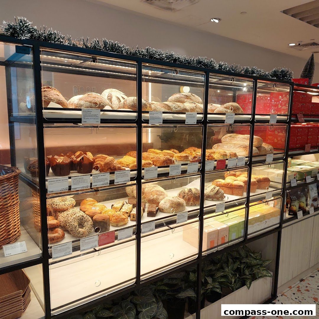 A display case filled with various freshly baked breads, pastries, and cakes at Cedele Bakery Cafe.