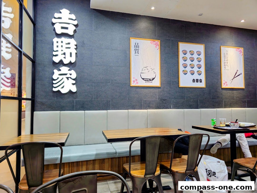 Interior of a Yoshinoya restaurant with seating, tables, and decorative posters on the wall.