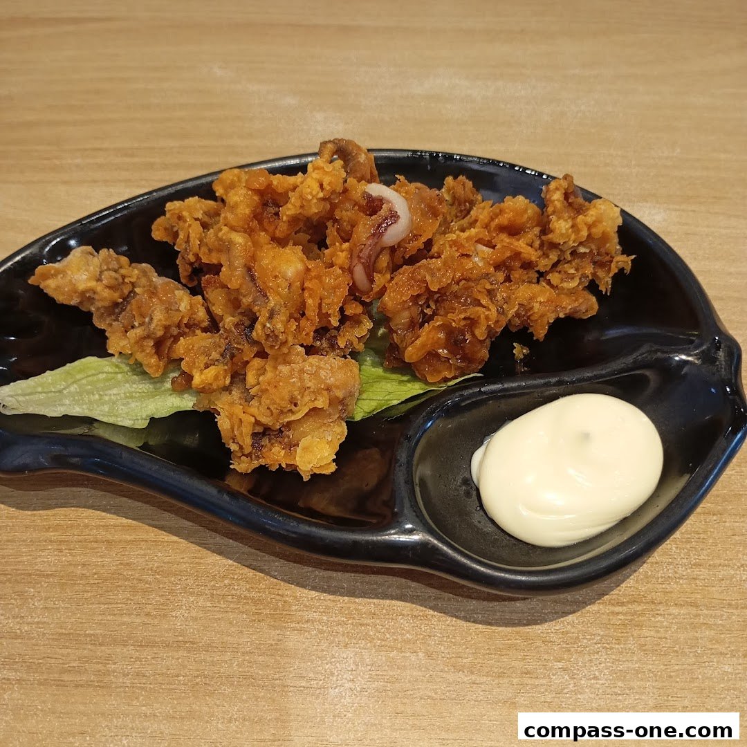 A plate of crispy fried calamari served with mayonnaise and lettuce on a wooden table.