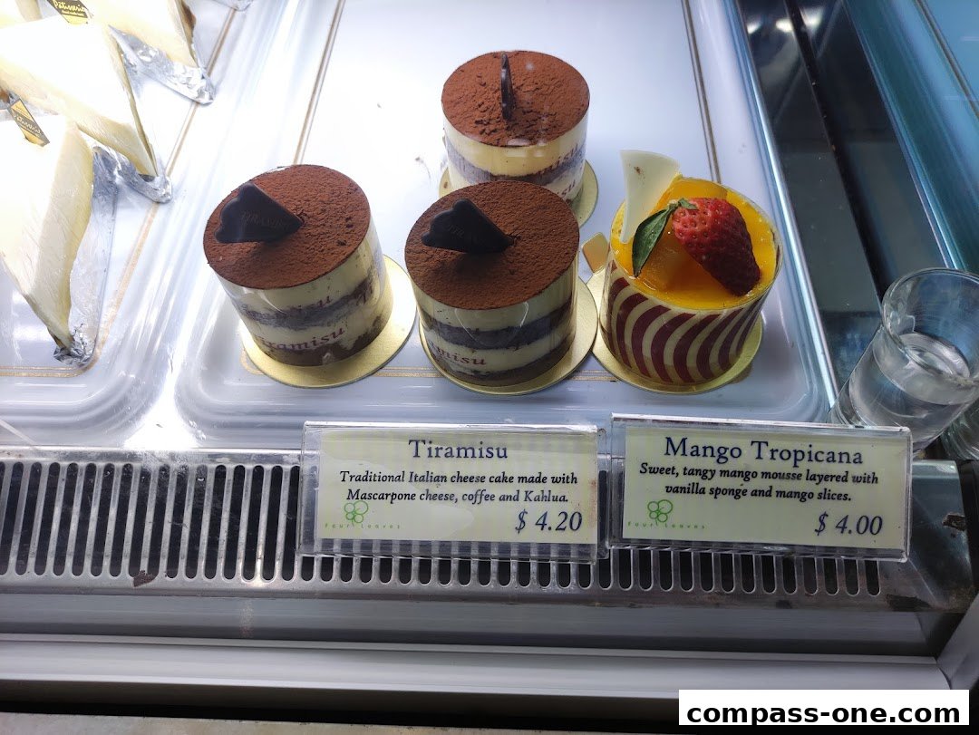 A display case filled with delicious-looking cakes, including Tiramisu and Mango Tropicana.