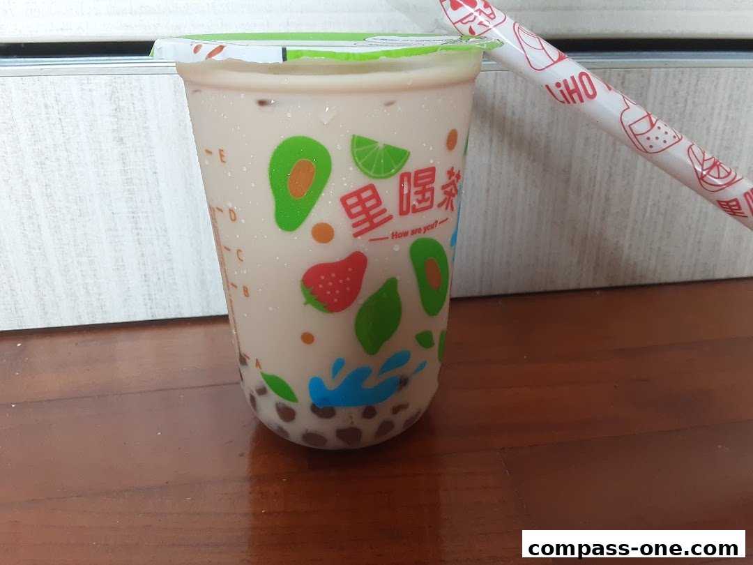 A close-up of a LiHO TEA bubble tea with fruit designs and a branded straw.