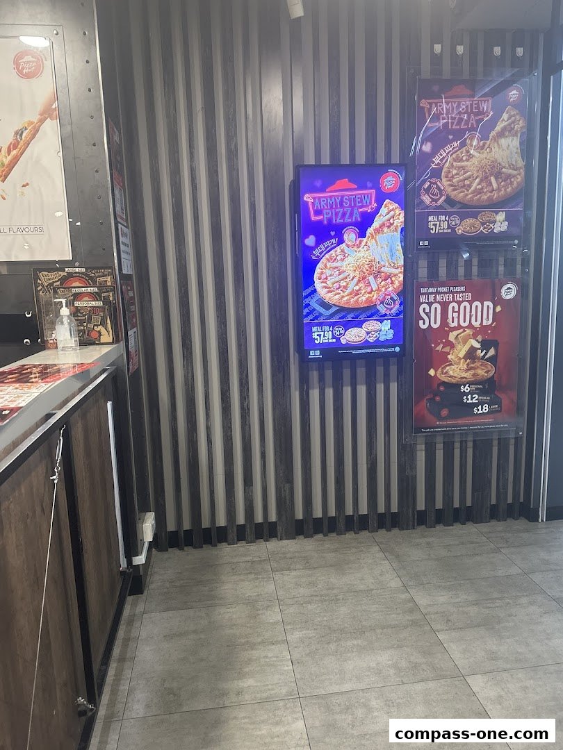Pizza Hut interior with digital menu boards displaying pizza promotions.