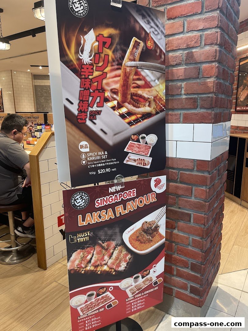 Promotional signs for Yakiniku Like featuring spicy squid and laksa flavored grilled meats.