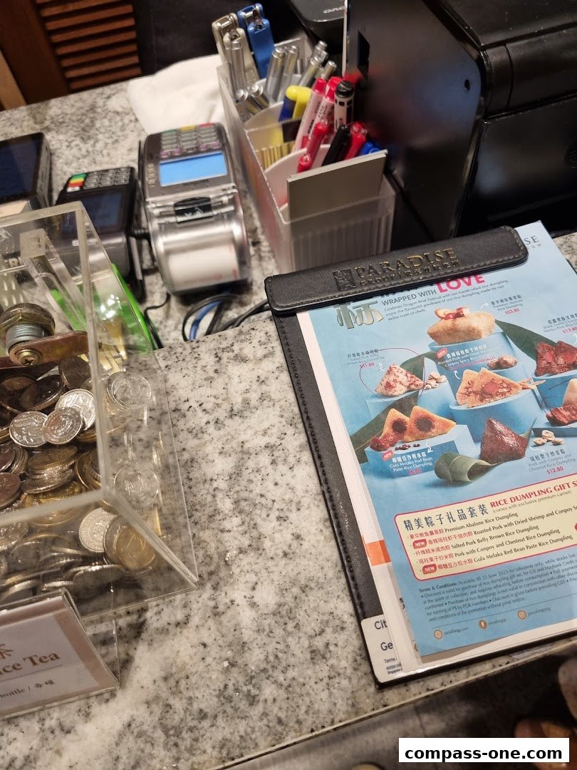 A close-up of a restaurant counter with payment terminals, pens, and a menu featuring rice dumplings.