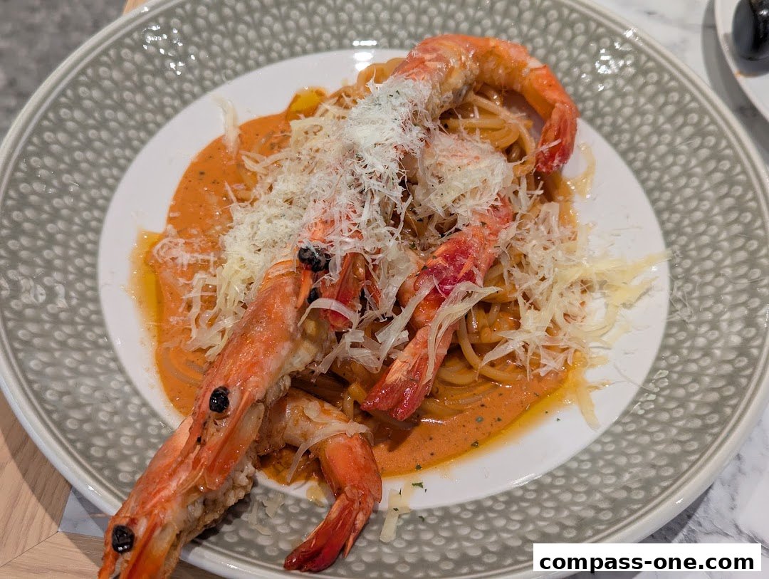 A plate of spaghetti with prawns in a creamy sauce, topped with grated cheese.
