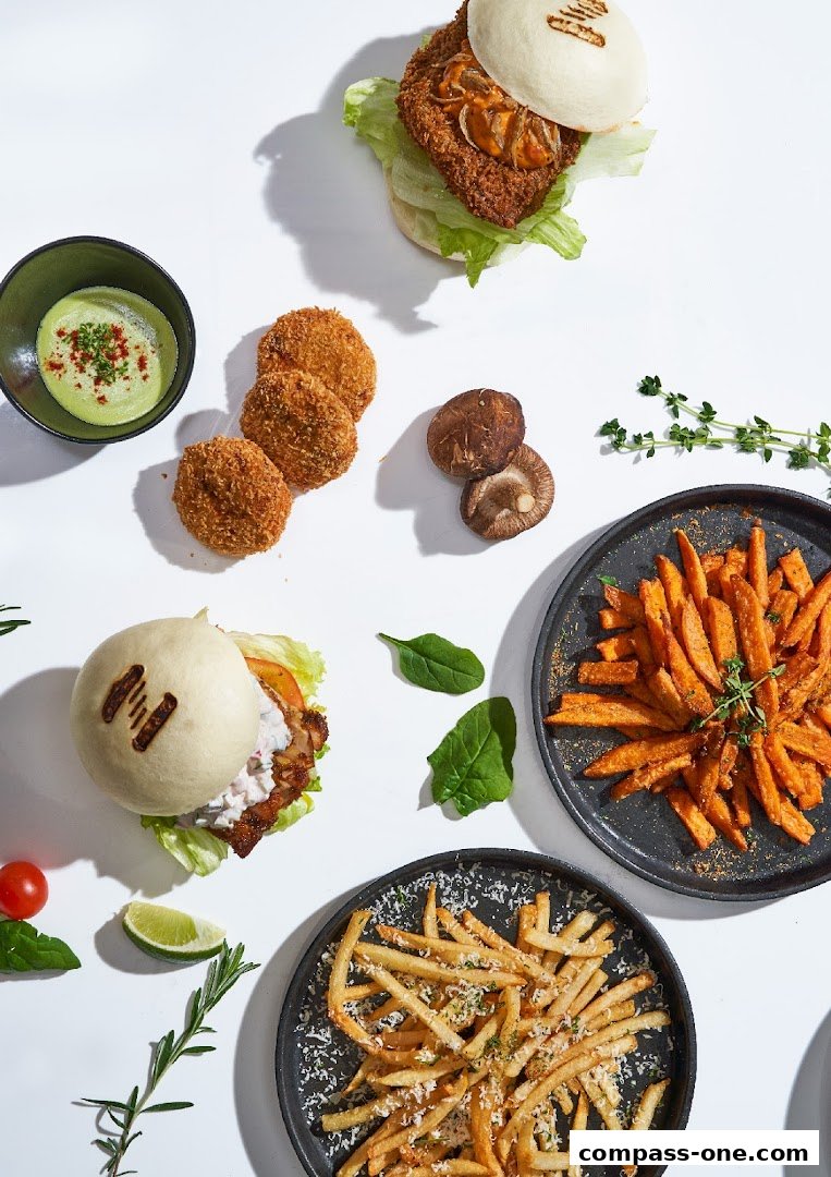 A spread of delicious food including bao buns, fries, and croquettes on a white background.