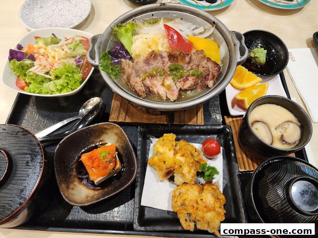 A close-up of a Japanese meal set with grilled meat, salad, tempura, and chawanmushi.