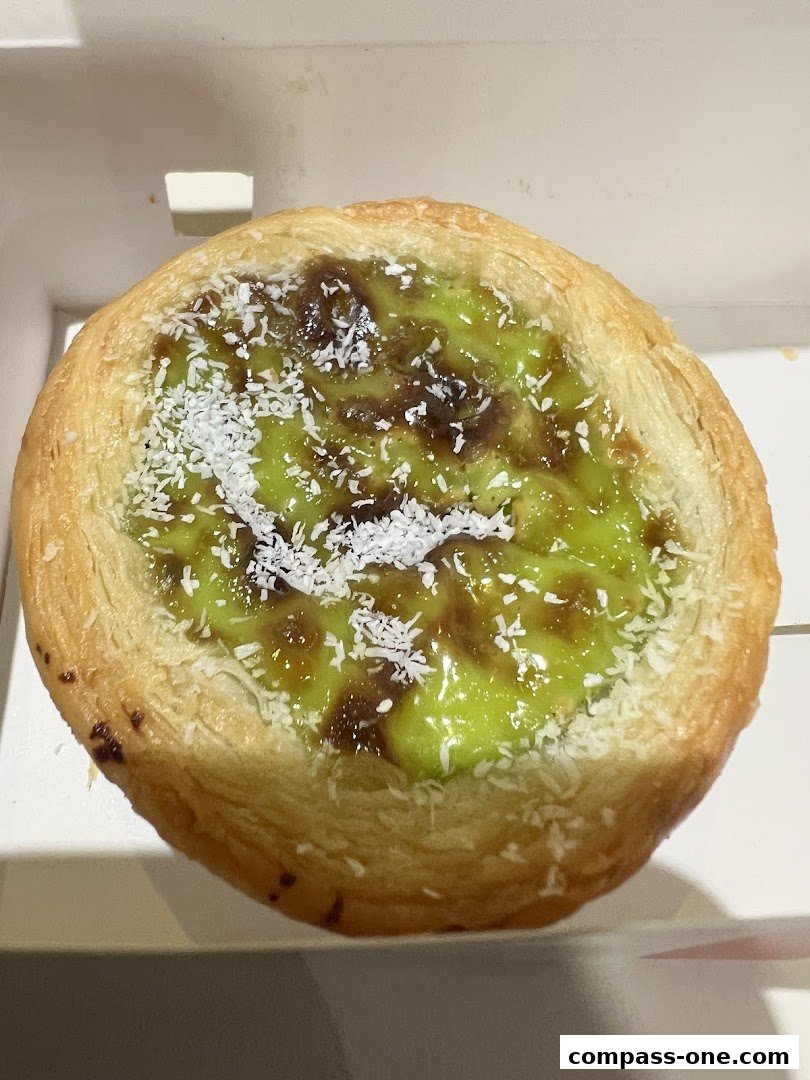 A close-up shot of a delicious-looking pastry with green filling and shredded coconut.