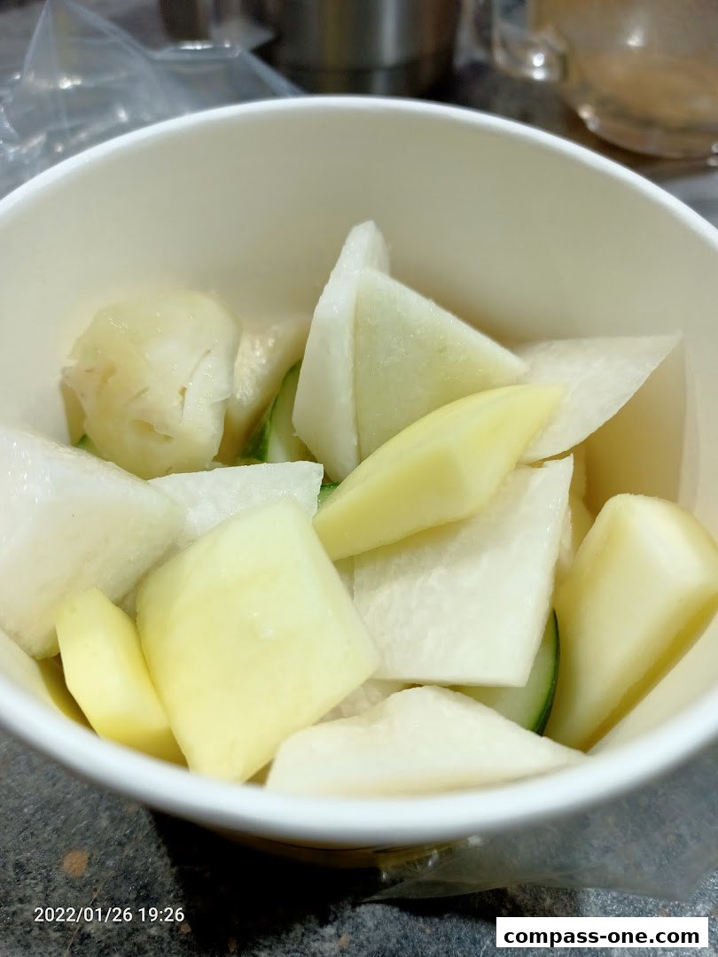 A close-up shot of a bowl filled with chopped vegetables, including radish and potato.