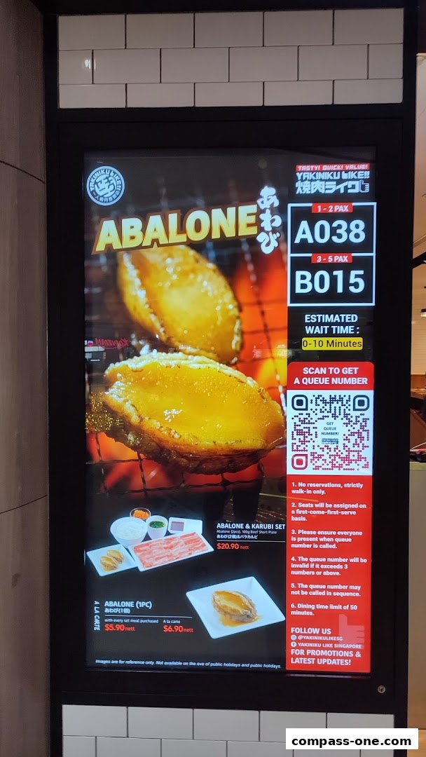 A digital display showing abalone dishes and queue information for Yakiniku Like.