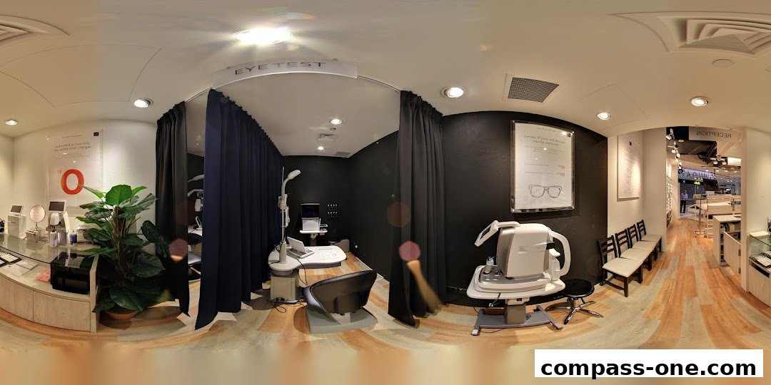 Interior view of an optical shop with eye testing equipment and a reception area.