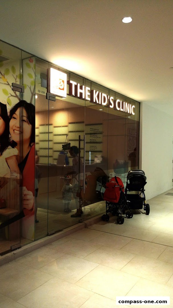 The entrance of 'The Kid's Clinic' with a large glass facade and strollers outside.