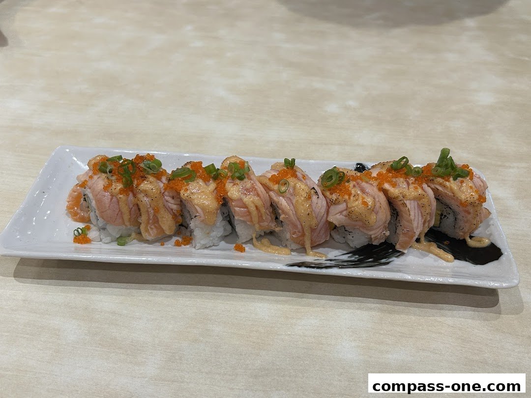 A plate of delicious sushi rolls topped with salmon, sauce, and green onions.