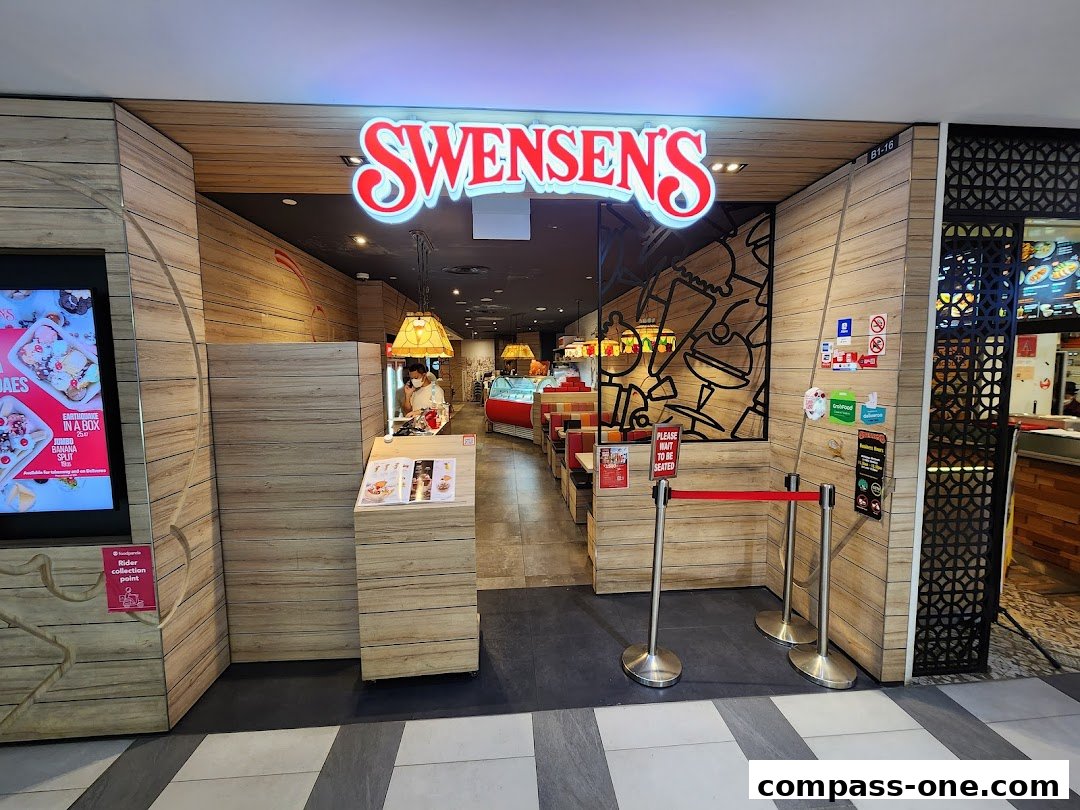 The entrance to Swensen's Compass One, featuring a prominent sign and seating area.