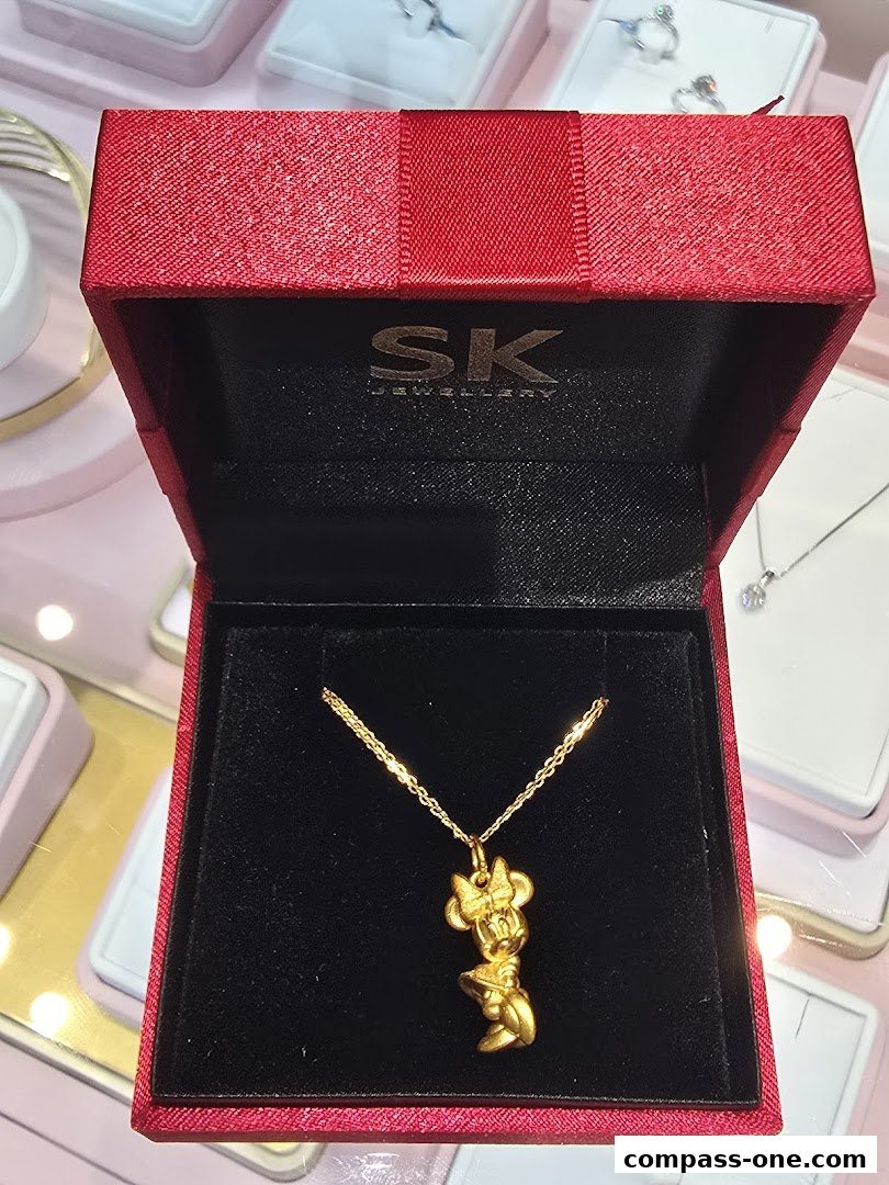 A gold Minnie Mouse pendant necklace displayed in an open red jewelry box.