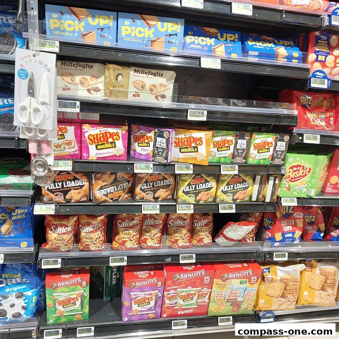 Shelves stocked with various snack crackers and biscuits, including Shapes, Ritz, and Arnott's.