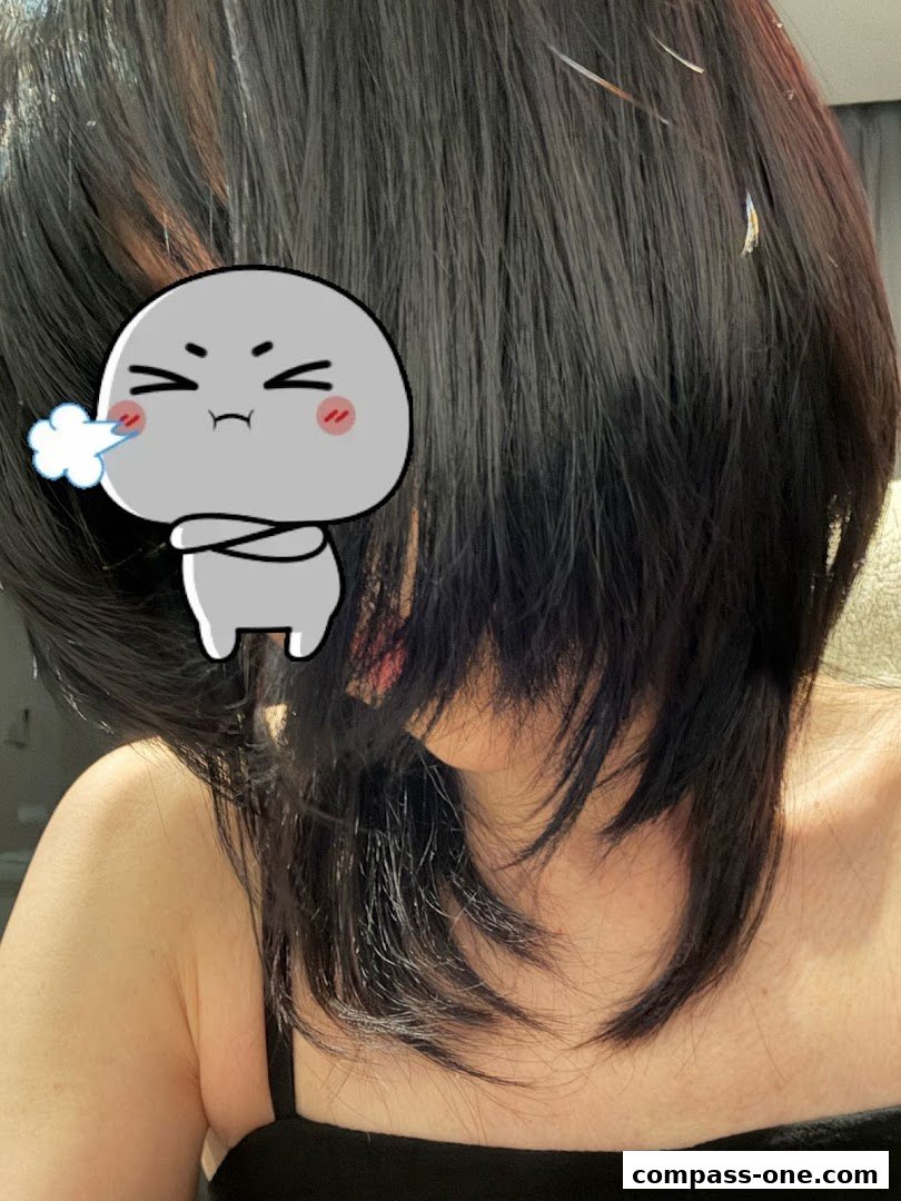 A person with dark, layered hair, partially obscured by a cartoon sticker.