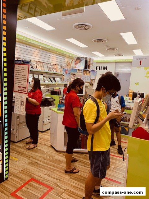Customers and staff inside a retail store with social distancing markers on the floor.