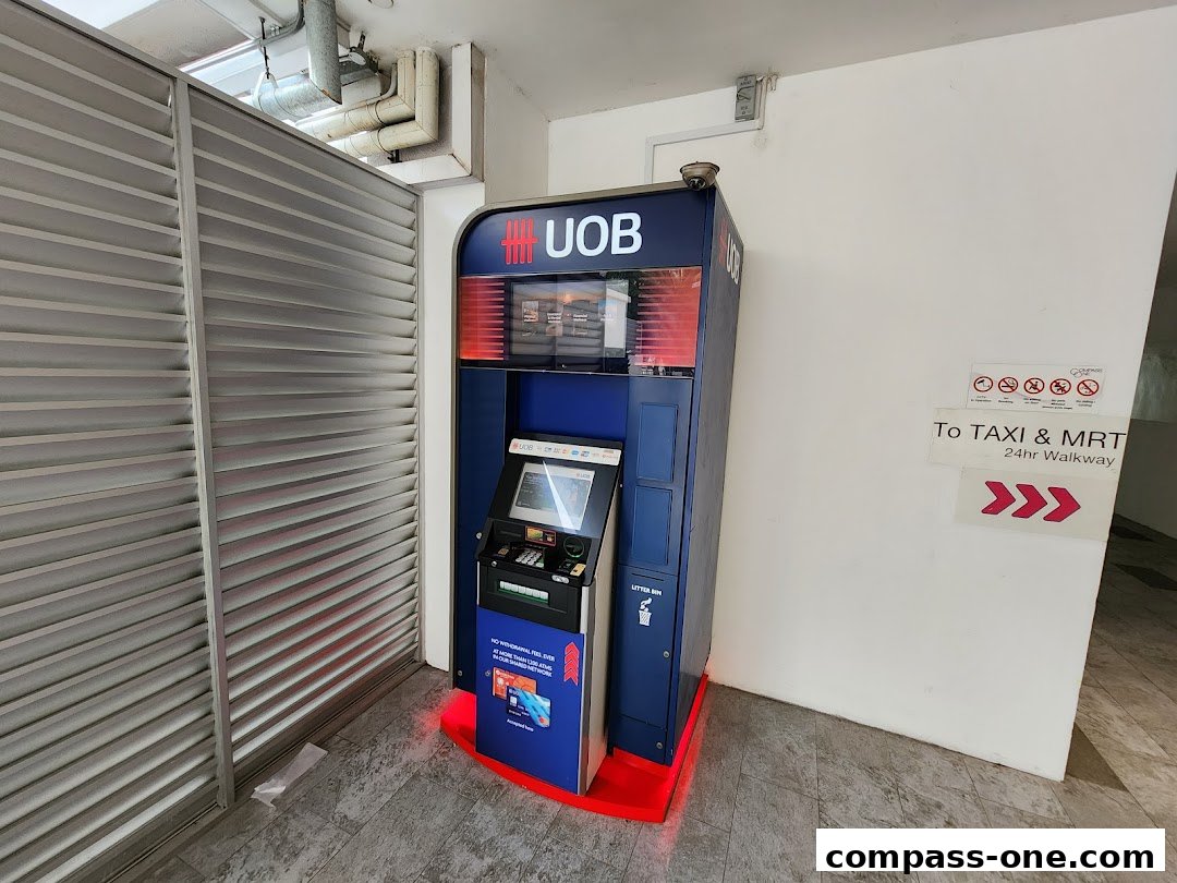 A UOB ATM machine is located next to a wall with directional signage.