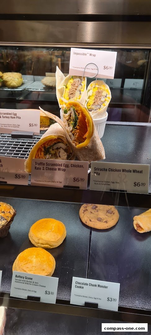 A display case filled with various wraps, scones, and cookies with price labels.