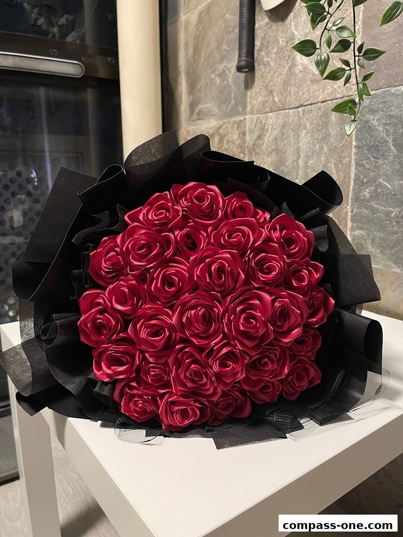 A beautiful bouquet of red satin roses wrapped in black paper and netting.