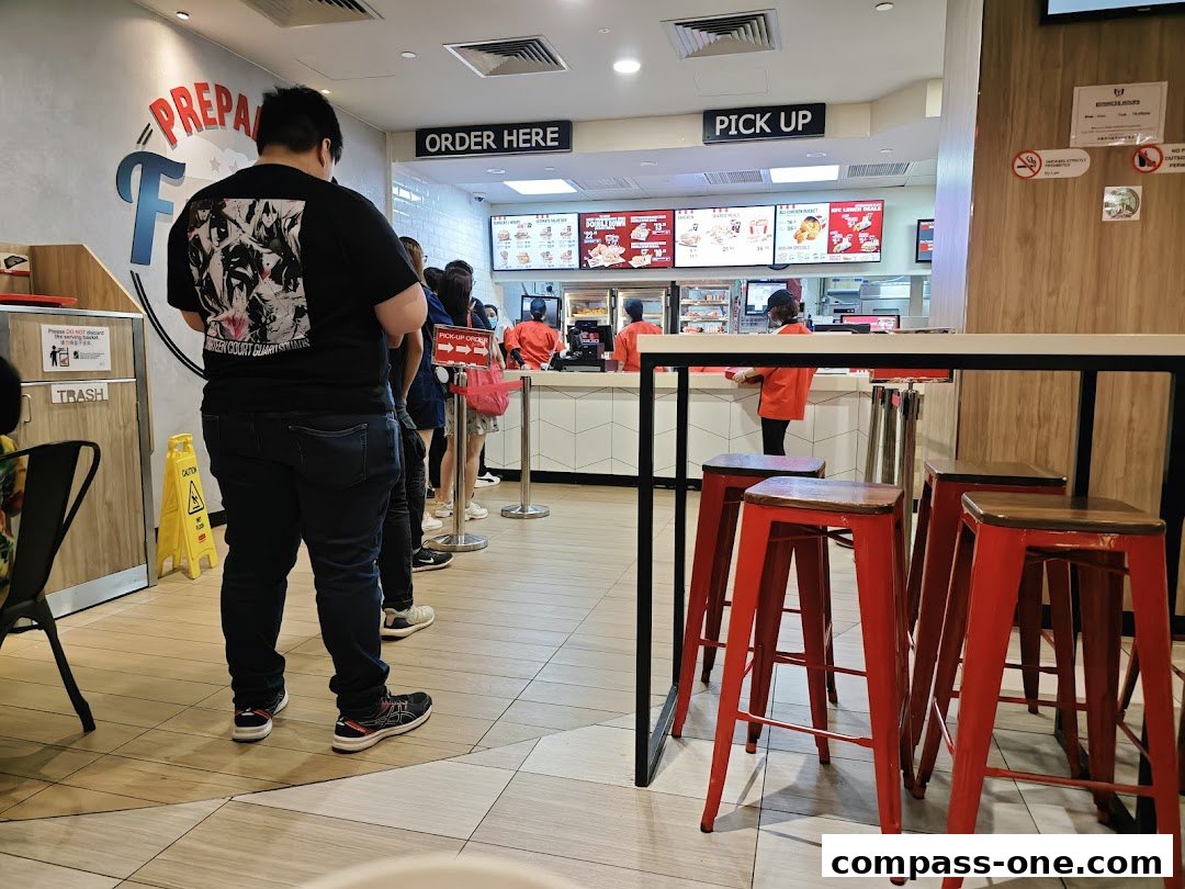 Customers queue at KFC for orders, with a counter and seating visible.