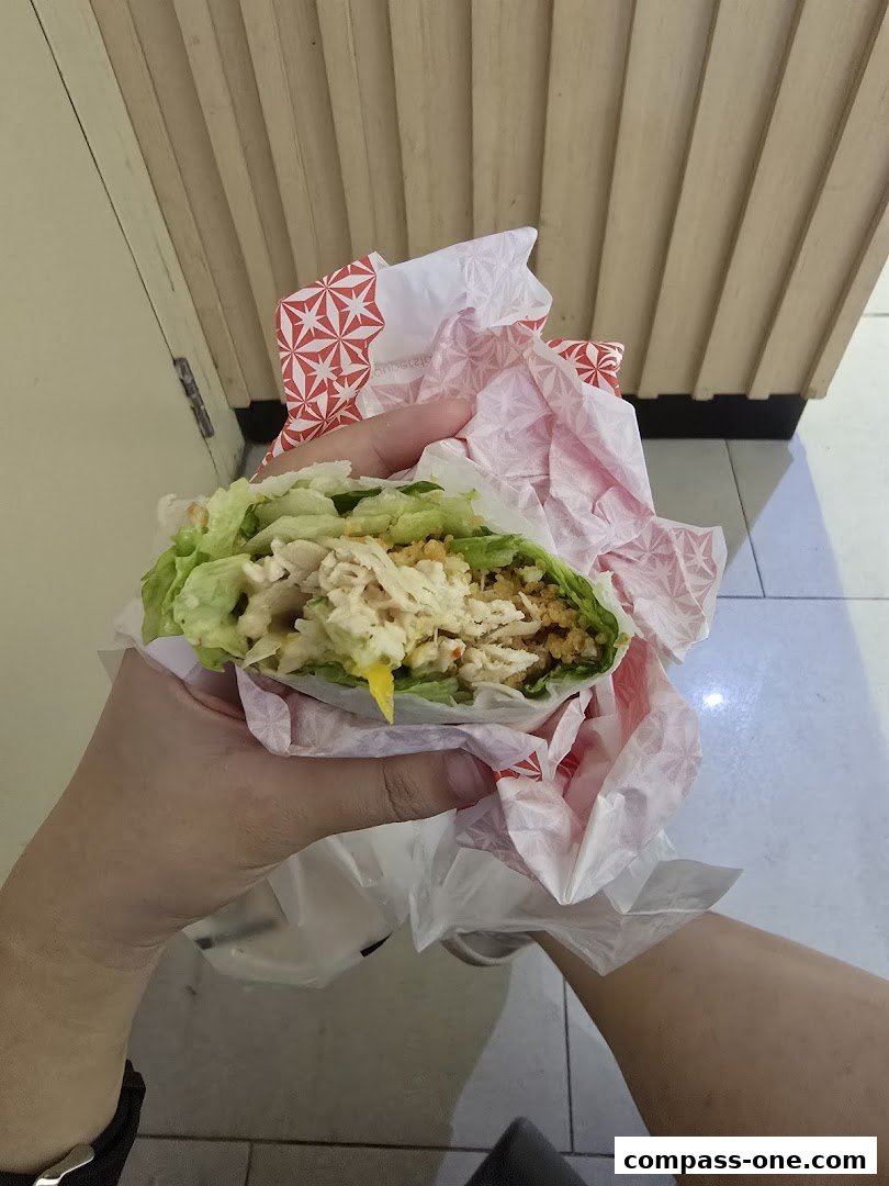 A person holds a healthy lettuce wrap filled with chicken and vegetables.