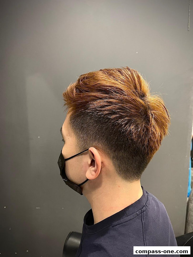 A person with a stylish haircut and dyed hair, wearing a mask.
