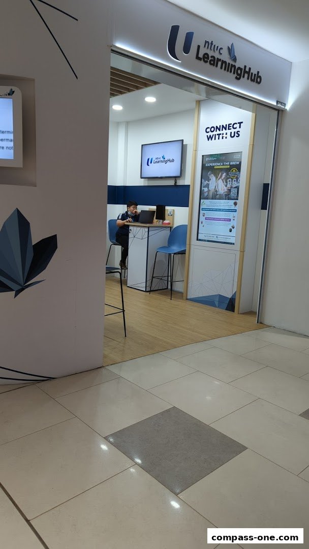 The entrance of NTUC LearningHub with a person working at a laptop and promotional displays.