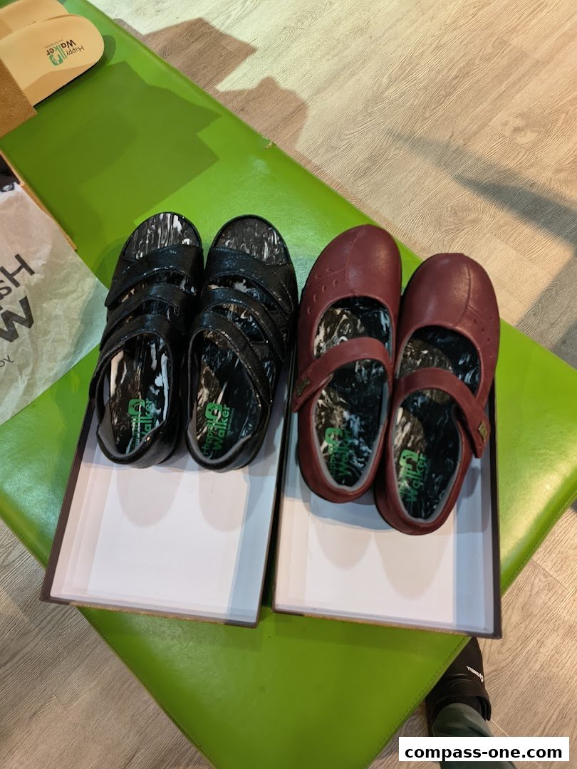 Two pairs of Happy Walker shoes, one black and one burgundy, displayed in boxes.