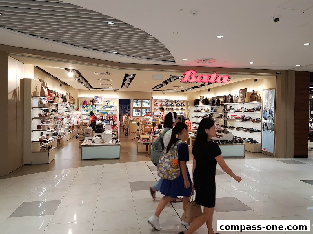 People walk past a Bata shoe store displaying a wide variety of footwear and handbags.